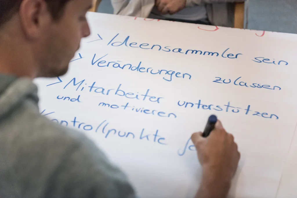 Nahaufnahme Teilnehmer schreibt etwas auf Flipchart bei gemba.basic Training